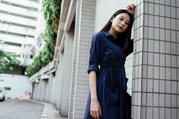 Linda Jovem Mulher Asiática Vestido Azul Inclinando Parede Branca Olhando — Fotografia de Stock