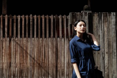 Kırsal ahşap duvarda, eski semtte ve eski evde mavi elbiseli güzel Asyalı bir kadın..