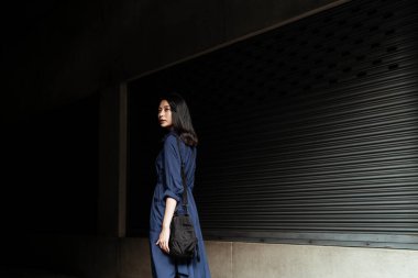 Mavi elbiseli güzel Asyalı kadın Karanlık Sokak 'a doğru yürüyor..