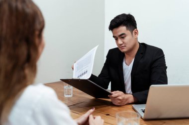 Yeni başvuran kadınla görüşürken Asyalı patron özgeçmişi okuyor..