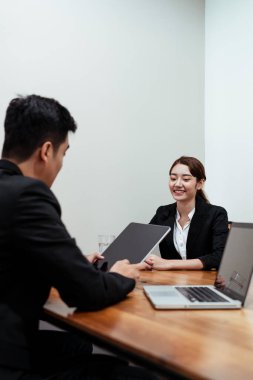 İnsan Kaynakları uzmanı tabletten özgeçmiş okuyor. İş görüşmesi yapıyor. Neşeli Asyalı kız..
