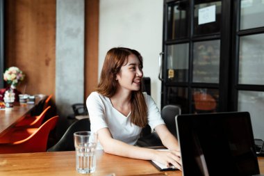 Evinde ahşap masada çalışan neşeli Asyalı kadın..