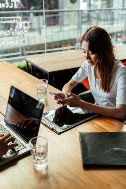 Şehirdeki kafede çalışırken akıllı telefon kullanan Asyalı genç bir kız..