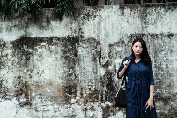Gyönyörű Fiatal Ázsiai Kék Ruhában Fekete Táskát Cipelve Piszkos Falnál — Stock Fotó