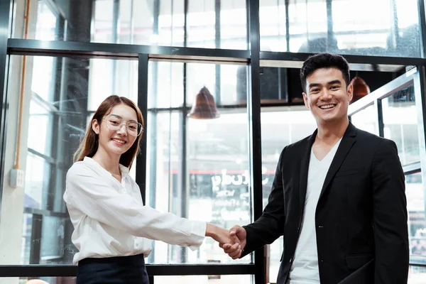 Cheerful asian boss and employee shaking hand after reach the gold in the quarter.