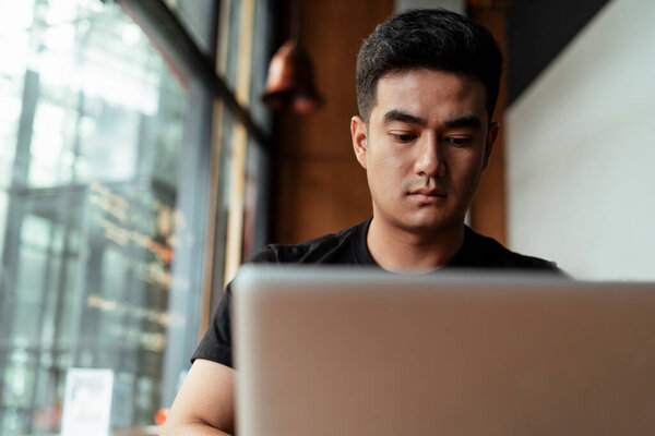 Mature thai guy working on laptop with serious looking at home.