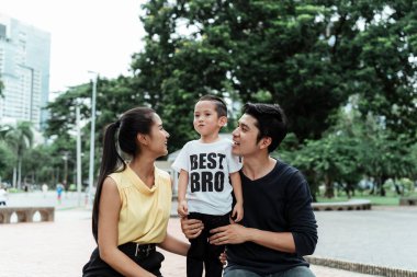 Anne ve baba, parkta aileleriyle vakit geçirirken oğullarıyla konuşuyorlar..