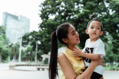 Bekar anne oğlunu taşıyor ve hafta sonu parkta konuşuyor..