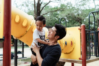 Baba oğlunu parkın parkında taşıyor..