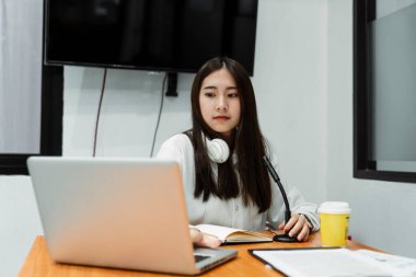 İnternetteki bilgileri sevimli gülüşüyle kontrol etmek için bilgisayarın ekranına bakan kadın DJ..