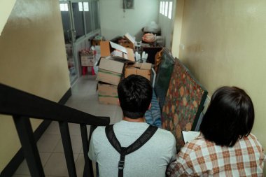 Tamirci ve tamirci kadın merdivende oturuyor, ortalığı temizlemeden önce önlerindeki dağınık şeylere bakıyorlar..