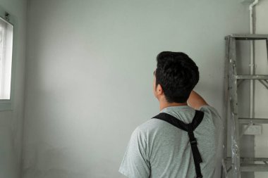 İnşaat alanındaki beton duvarı kontrol etmeye çalışan tamirci..