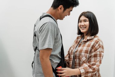 Yakışıklı Asyalı kadın, tamirci olarak işe gitmeden önce kocasının hazırlanmasına yardım ediyor..