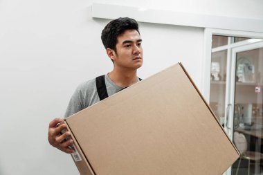 Asyalı tamirci büyük bir kutu taşıyor. Teslimatçı iyi bir kutu kaldırıyor. Taşıma hizmeti için ağır paket taşıyan bir adam. El ulaşımı.
