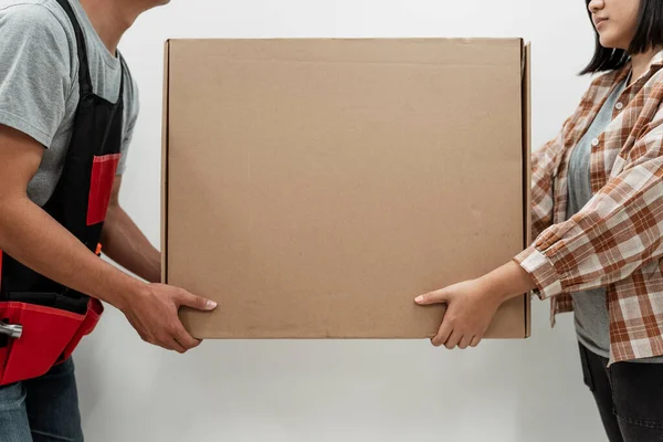 Man and woman moving a big box together. Copy space in the middle.