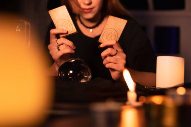 Uzun saçlı güzel kadın falcı karanlık odada geleceği tahmin etmek için tarot kartını kullanıyor..