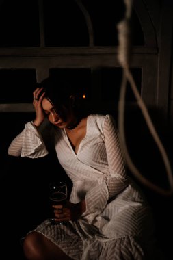 İş yerindeki üzgün kadın, elinde bir kadeh şarapla sallanarak odada oturuyor. İntihar et..