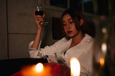 Resmi giyinmiş güzel sarhoş iş kadını gece evde kırmızı şarap içiyor..