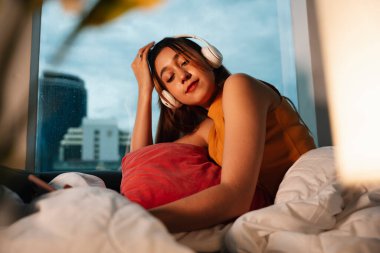 Güzel melez kadın geceleri kablosuz kulaklıkla müzik dinlemekten hoşlanır..