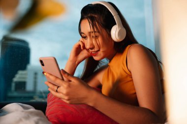 Güzel melez kadın geceleri kablosuz kulaklıkla müzik dinlemekten hoşlanır..
