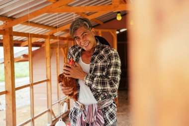 Çiftlikte çıplak elle tavuk tutan Asyalı yaşlı çiftçi..