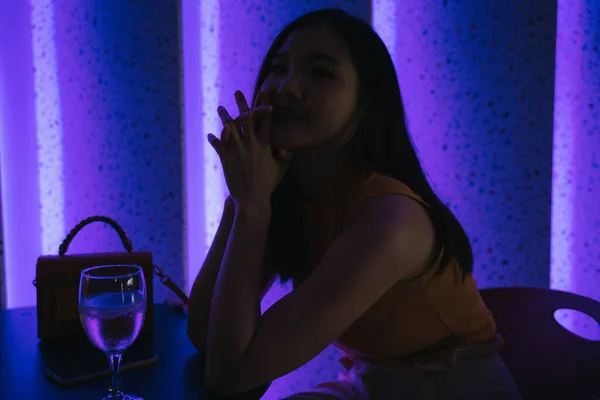 Beautiful asian thai woman in a night club bar under purple neon light.
