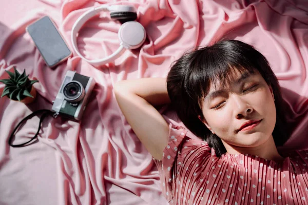 俯瞰全景 美丽的亚裔泰国人女人 短短的黑发睡在粉色的背景上 摄像头耳机智能手机Camera Headphone Smartphone 旅行梦想家 — 图库照片