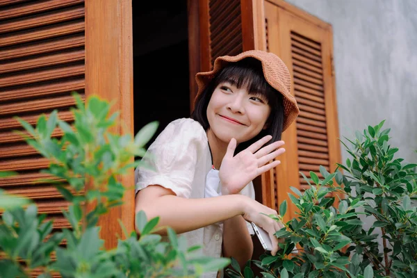 美丽的亚洲女人在酒店窗口挥手打招呼 地方企业 — 图库照片