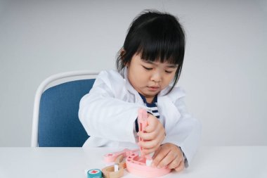 Güzel Asyalı Taylandlı çocuk dişçi oyuncağı rolünde oynuyor..