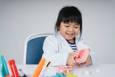 Güzel Asyalı Taylandlı çocuk dişçi oyuncağı rolünde oynuyor..