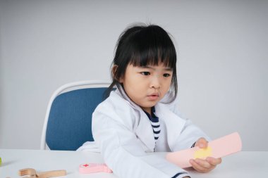 Güzel Asyalı Taylandlı çocuk hastanede hastalarla konuşurken doktor rolü oynuyor..