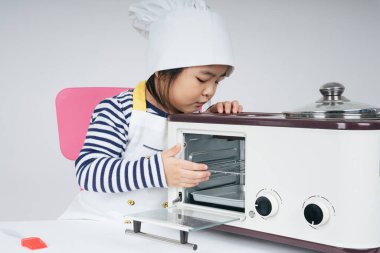 Güzel Asyalı Taylandlı çocuk fırında tatlı pişiren şef rolünde oynuyor..