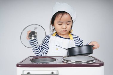 Güzel Asyalı Taylandlı çocuk fırınlı yemek pişirme istasyonunda şef rolünde oynuyor..
