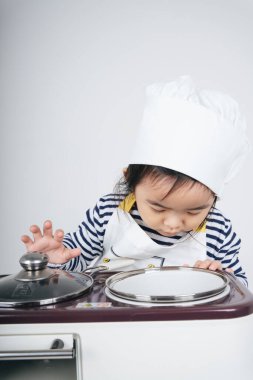 Güzel Asyalı Taylandlı çocuk fırınlı yemek pişirme istasyonunda şef rolünde oynuyor..