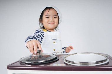 Güzel Asyalı Taylandlı çocuk fırınlı yemek pişirme istasyonunda şef rolünde oynuyor..