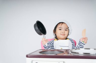 Güzel Asyalı Taylandlı çocuk aşçı olarak aşçı dükkanında haşlama kabıyla oynuyor..