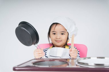 Güzel Asyalı Taylandlı çocuk aşçı olarak aşçı dükkanında haşlama kabıyla oynuyor..