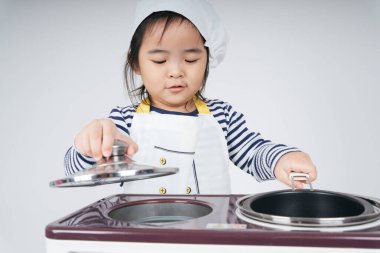 Güzel Asyalı Taylandlı çocuk fırınlı yemek pişirme istasyonunda şef rolünde oynuyor..