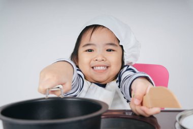 Güzel Asyalı Taylandlı çocuk soba istasyonunda aşçı olarak yemek pişiriyor..