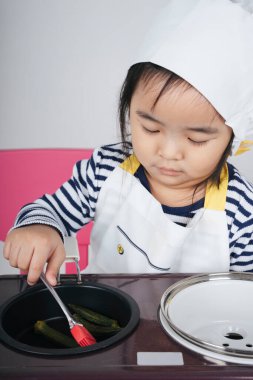 Güzel Asyalı Taylandlı çocuk soba istasyonunda aşçı olarak yemek pişiriyor..