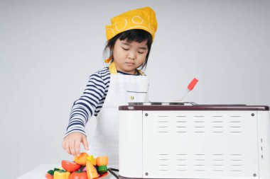 Güzel Asyalı Taylandlı çocuk mutfakta sarı bandajlı aşçı rolünde oynuyor..
