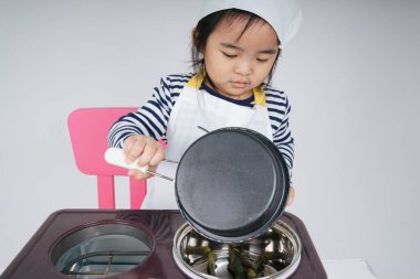 Güzel Asyalı Taylandlı çocuk soba istasyonunda aşçı olarak yemek pişiriyor..