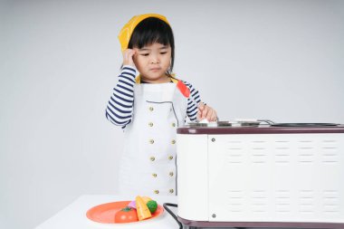 Güzel Asyalı Taylandlı çocuk mutfakta sarı bandajlı aşçı rolünde oynuyor..
