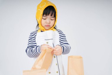 Güzel Asyalı Taylandlı çocuk, sarı bandajlı garsonluk yapıyor ve kese kağıdına yemek dolduruyor..