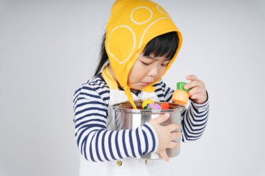 Güzel Asyalı Taylandlı çocuk, garsonluk yapıyor. Sarı bandaj takıyor, tencereye sarılıyor, beyaz arka planda soyutlanıyor..