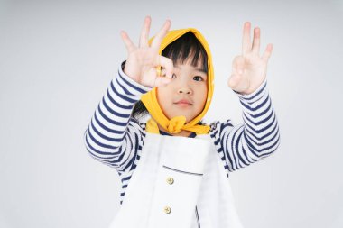 Sarı bandajlı yakışıklı Asyalı çocuk iki eliyle işaret veriyor..