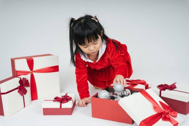 Noel Baba üniformalı, kar festivalini kutlamak için hediye kutulu güzel Asyalı çocuk..