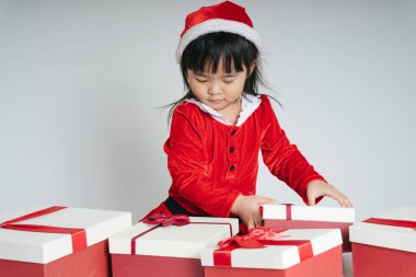 Noel Baba üniformalı, kar festivalini kutlamak için hediye kutulu güzel Asyalı çocuk..