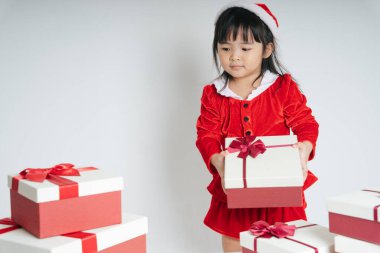 Noel Baba üniformalı, kar festivalini kutlamak için hediye kutulu güzel Asyalı çocuk..