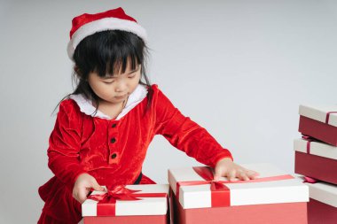 Noel Baba üniformalı, kar festivalini kutlamak için hediye kutulu güzel Asyalı çocuk..